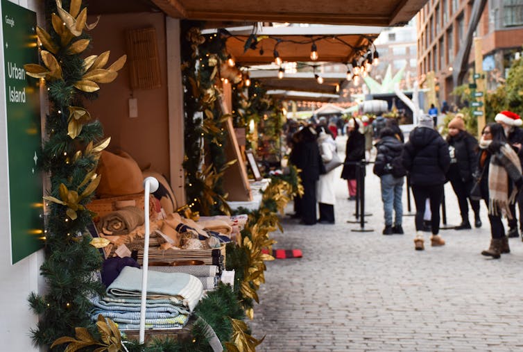 People walk down a cobble-lined street lined by vendor booths