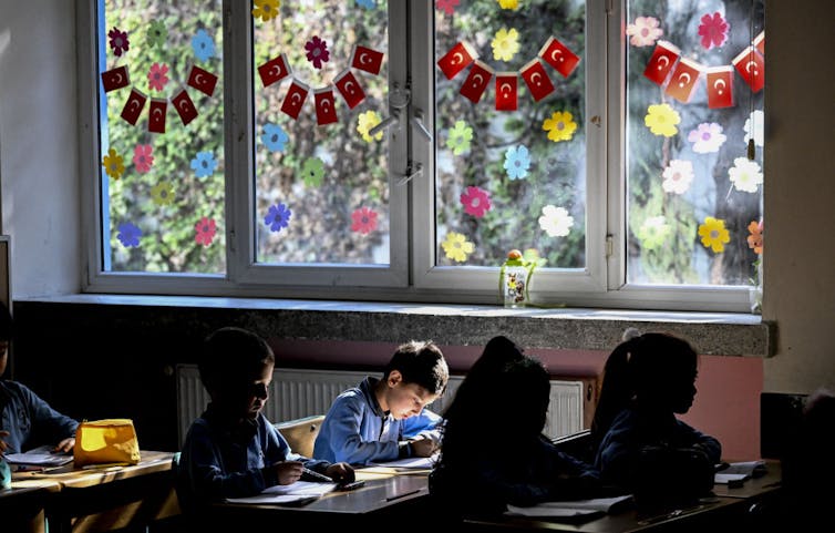 A peaceful scene inside a sunlit classroom with colorful decorations in the windows.