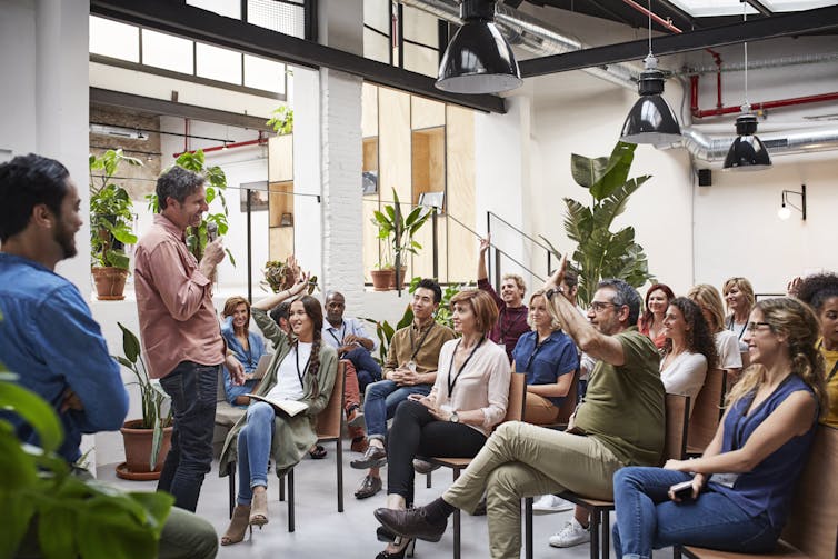 male standing with mic, seated audience, in a casual business seminar