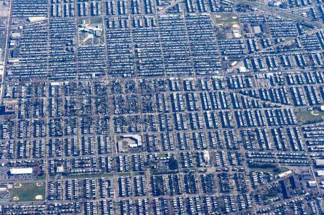 An aerial grid of housing with some green patches, playing field and parks mixed in.