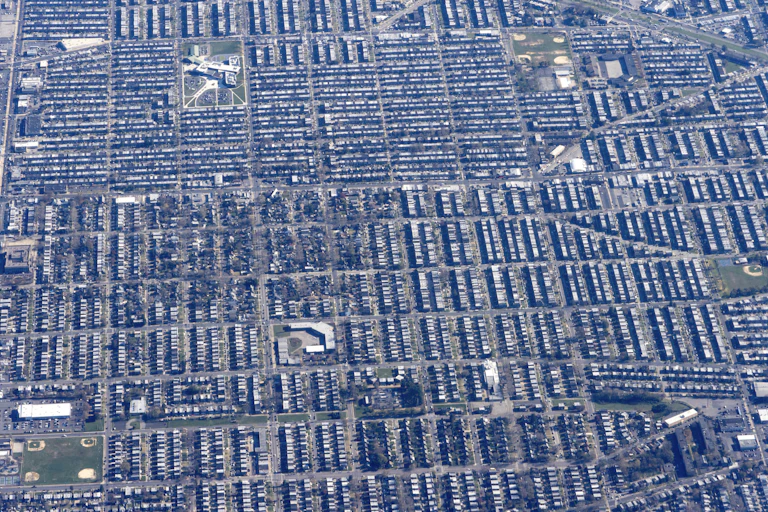An aerial grid of housing with some green patches, playing field and parks mixed in.