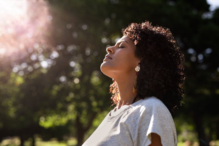 A black woman meditating in a park.