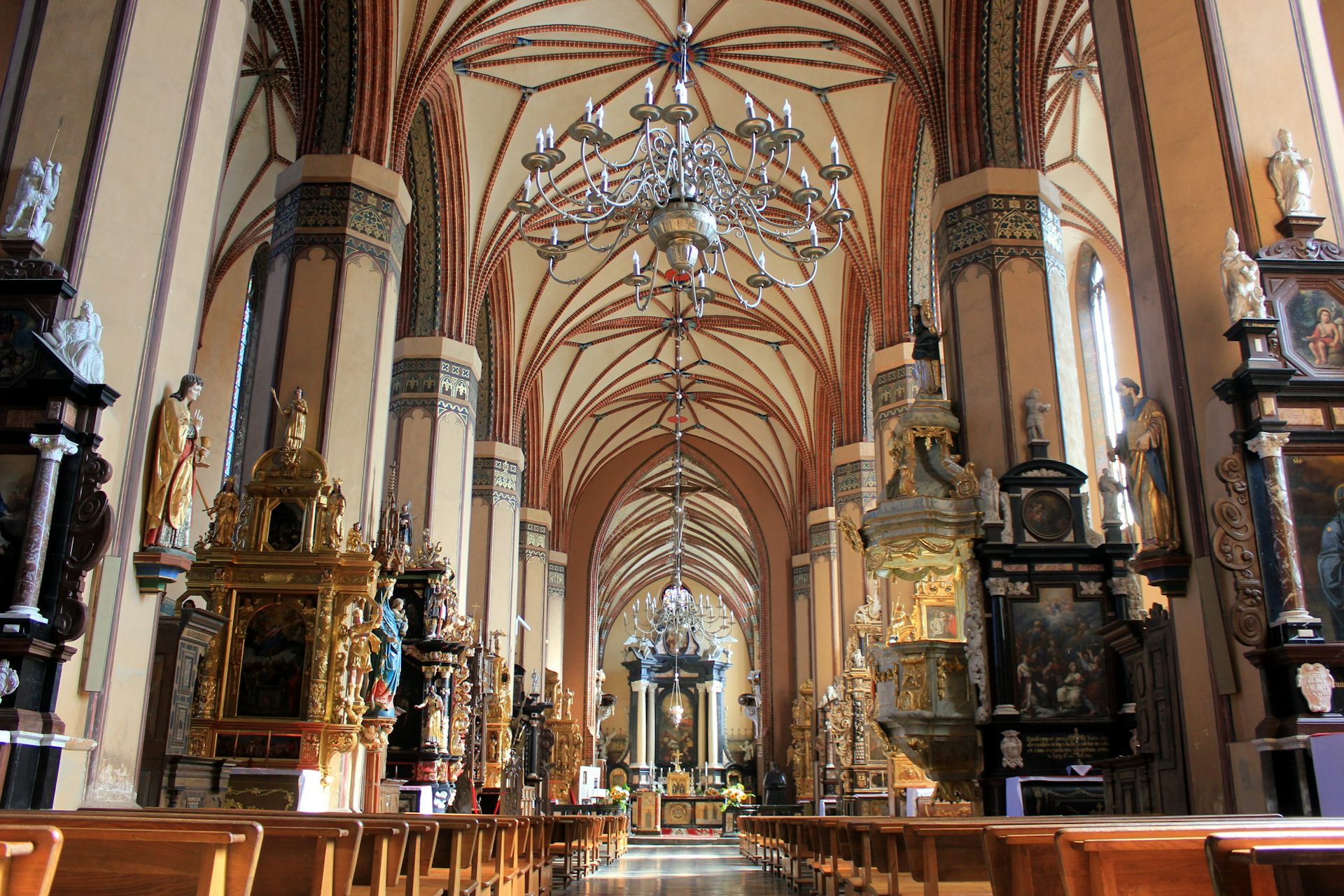 Photo of the inside of a cathedral with high vaulted ceiling, many columns and statues.