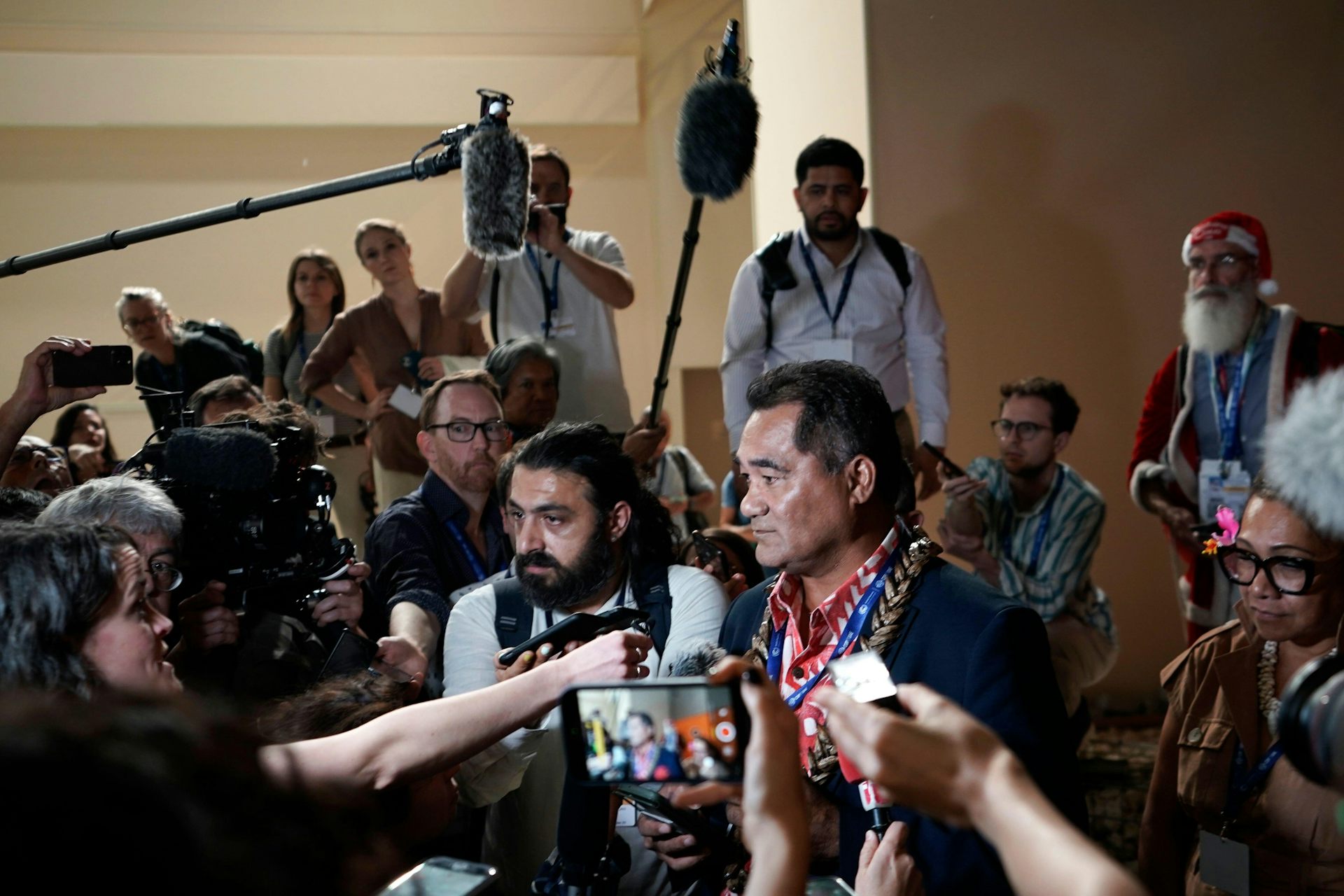 A man surrounded by cameras and microphones.