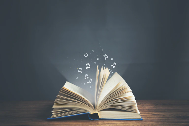 Un libro abierto expulsa notas musicales.