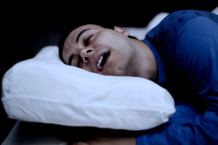 un homme dormant avec la bouche ouverte