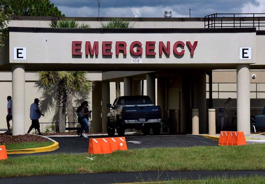 People walking past parked pickup truck into a hospital emergency room entrance
