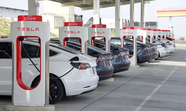 a row of electric Tesla vehicles being charged
