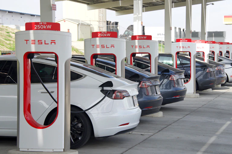 a row of electric Tesla vehicles being charged
