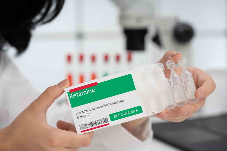 Medical person holding ampoules of ketamine