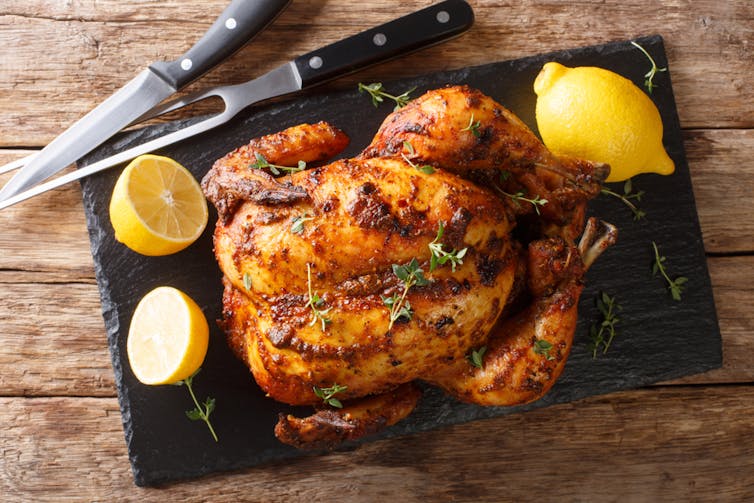 A roast chicken is displayed on a table.