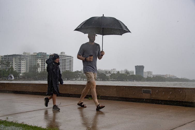 man and son walk under umbrella