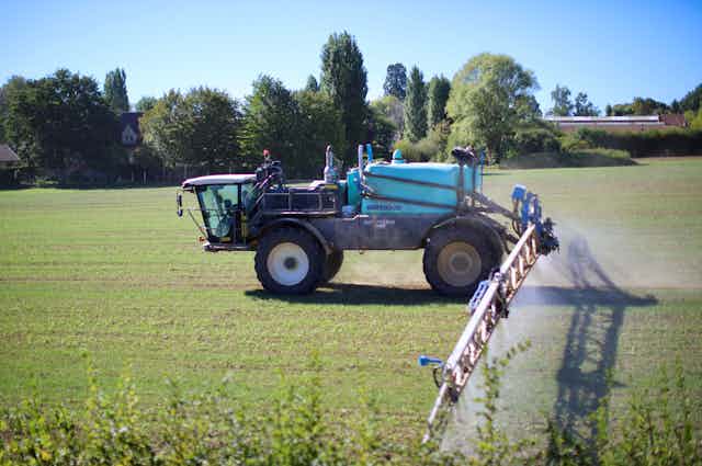 tracteur dans un champ qui épande des pesticide