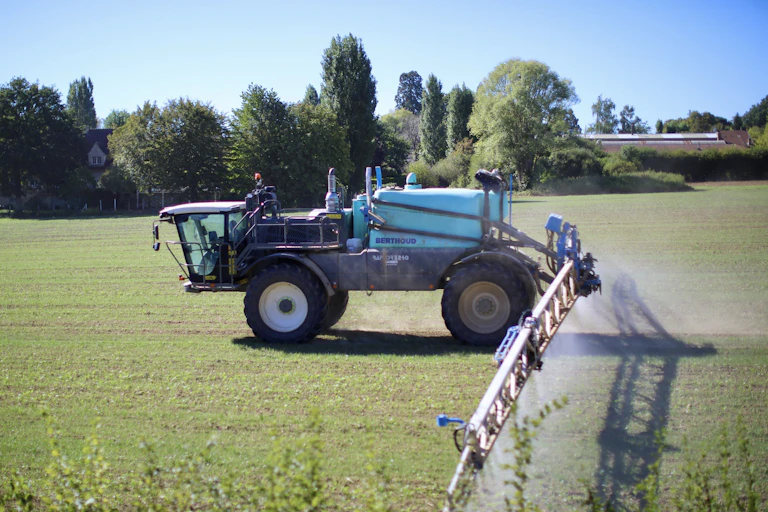 tracteur dans un champ qui épande des pesticide