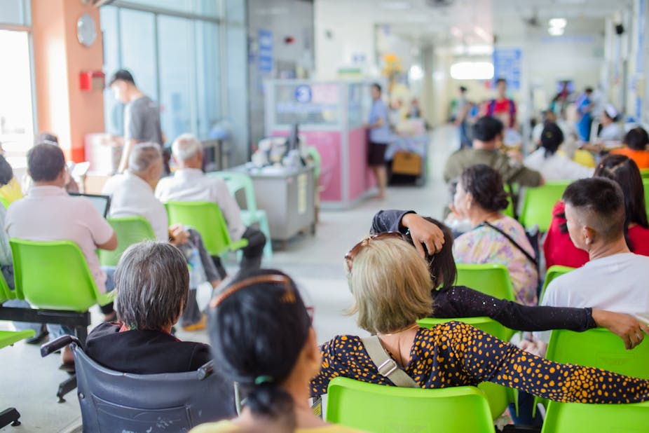 People waiting in chairs in a hospital waiting room.
