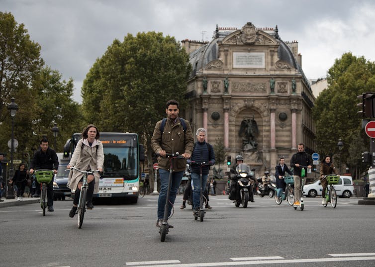 People on bikes, e-scooters, motorbikes and buses in Paris.