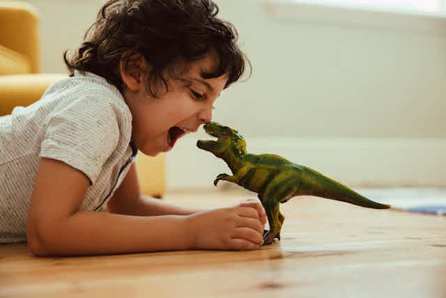Boy playing with toy T-Rex on the floor