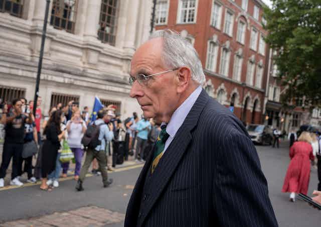 Peter Bone walking in Whitehall with a crowd in the background.