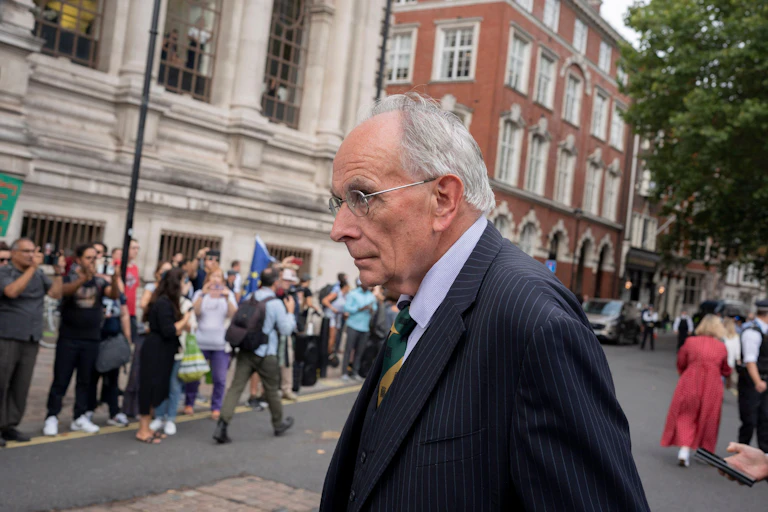 Peter Bone walking in Whitehall with a crowd in the background.