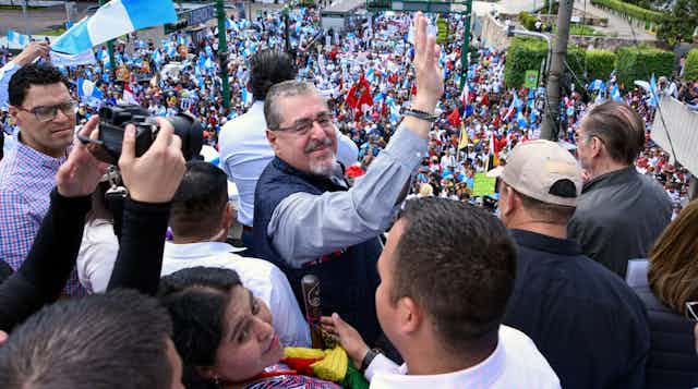 Guatemala's president-elect Bernardo Arevalo stands and waves surrounded by large crowd