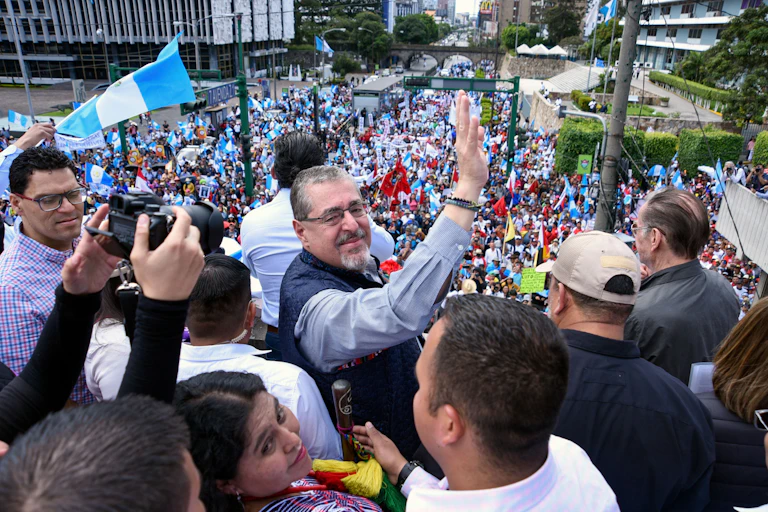 Guatemala's president-elect Bernardo Arevalo stands and waves surrounded by large crowd