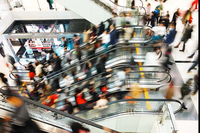 The blurred motion of people on escalators at a centre shopping centre