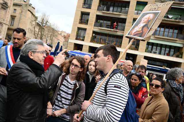 Un manifestant tient une pancarte "Mort au roi", alors qu'il écoute le dirigeant du parti La France Insoumise, Jean-Luc Mélenchon, lors d'une manifestation contre la réforme des retraites, à Marseille, le 23 mars 2023. 