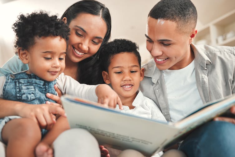 A man, a woman and two children reading a book together