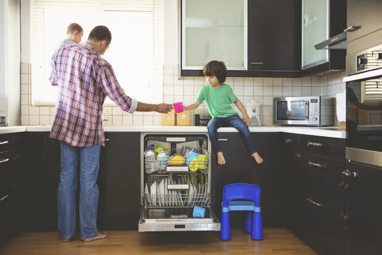 Man with children stacking dishwasher