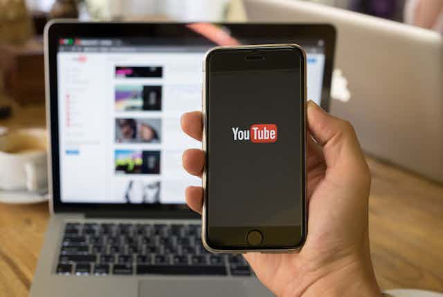 Hand holding phone with YouTube logo