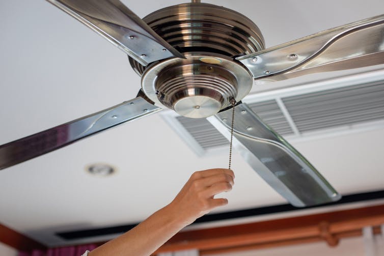 A person turns on a ceiling fan.