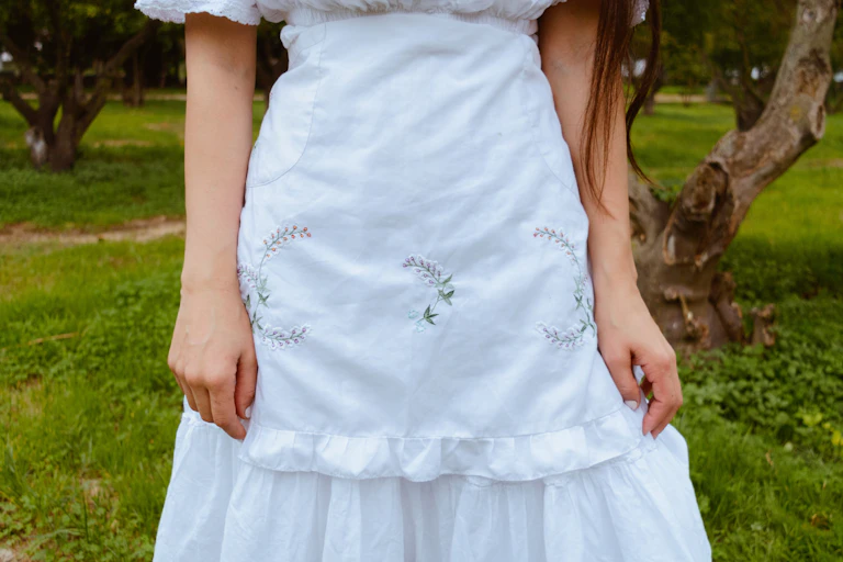 a woman with long hair in a white dress and white apron