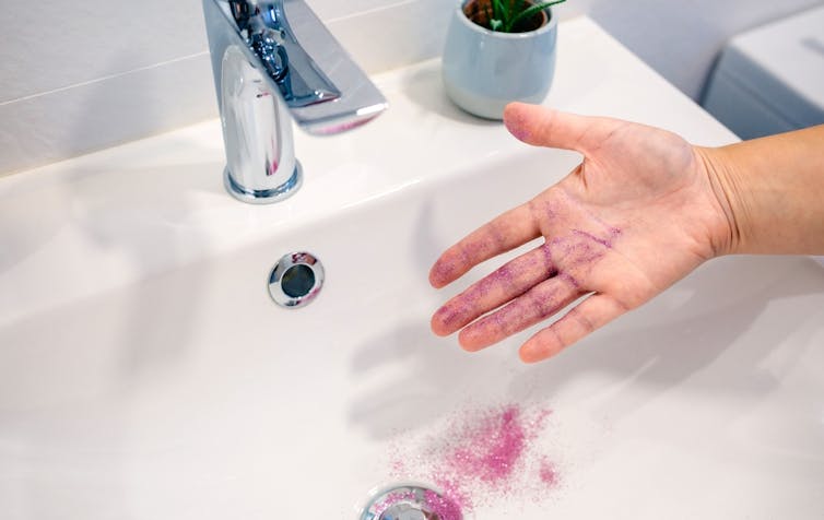 Glitter being washed off a hand in the sink