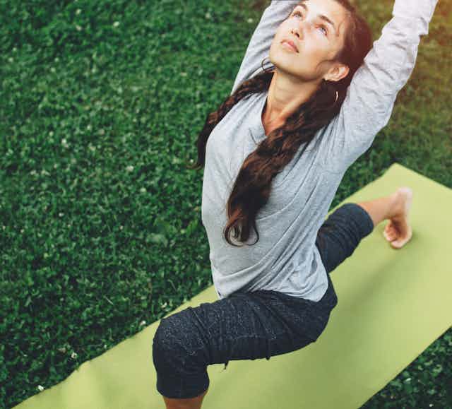 Une femme est debout dans une posture de yoga.