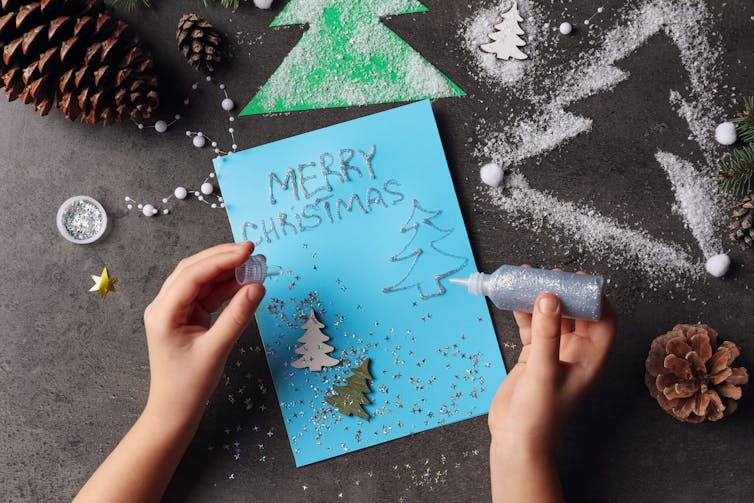 Child putting glitter on christmas card