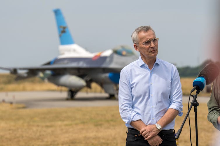 NATO secretary general Jens Stoltenberg in front of an F-16 fighter aircraft.