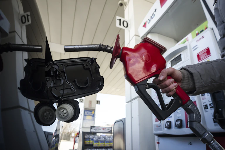 A gas pump seen close to the gas tank of a car.