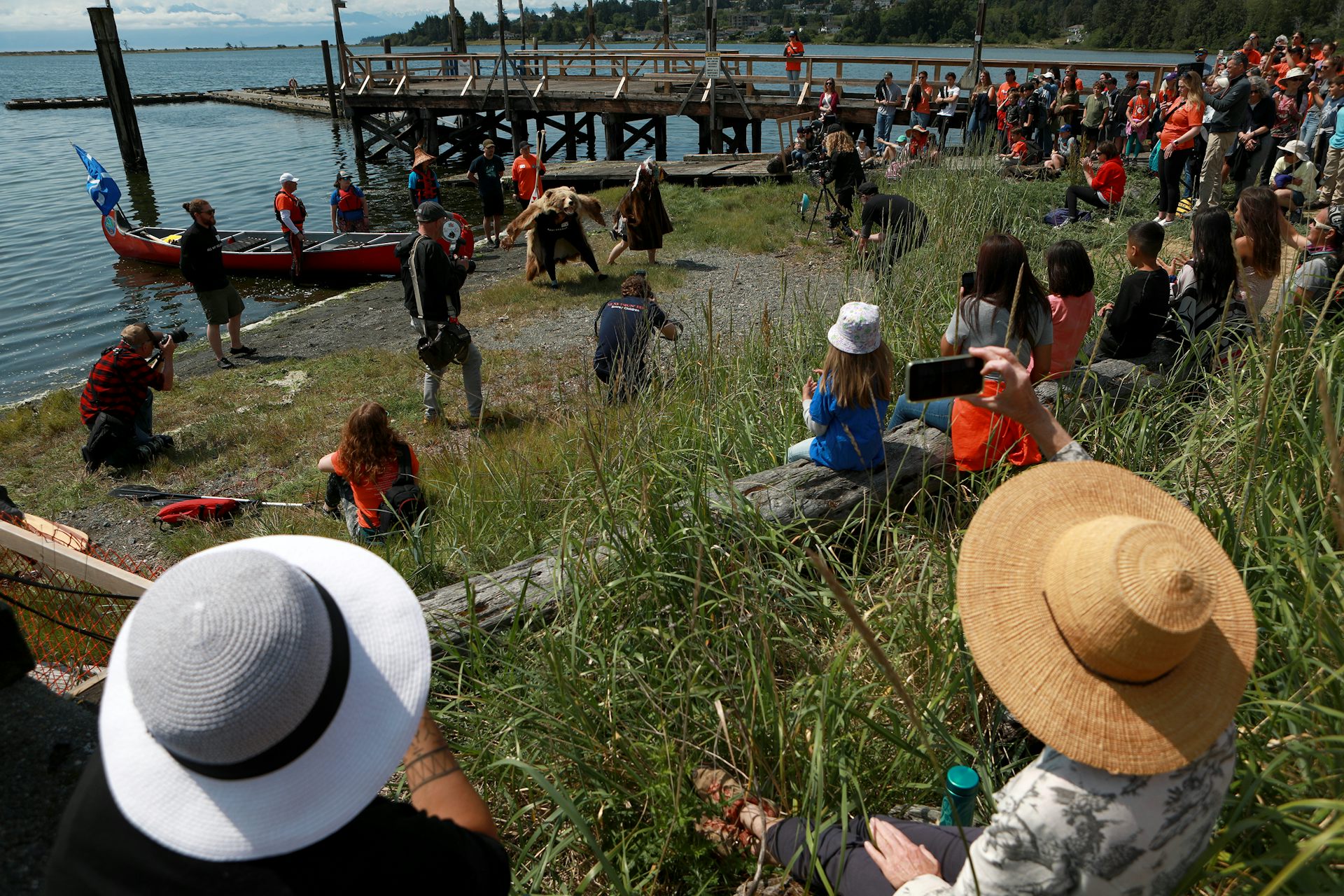 People stand near water, some with a canoe.