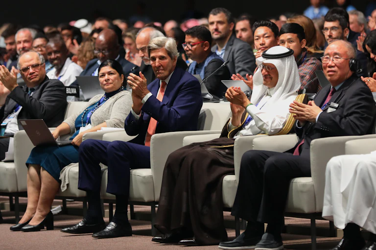 People sit in plush chairs in the front, with desks behind them for the rest of the world's negotiators.
