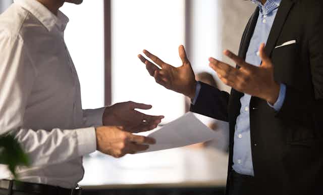 Two men in business attire gesturing while they speak