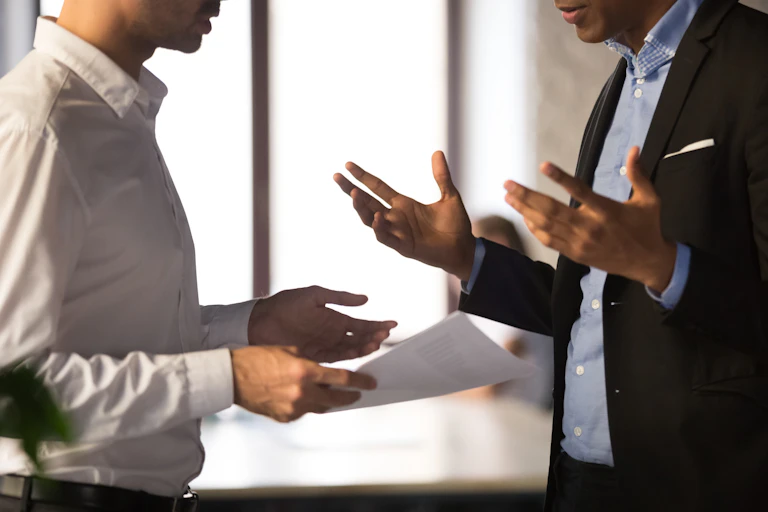 Two men in business attire gesturing while they speak