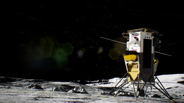 A lunar lander on the gray surface of the Moon. The lander has a square gold, reflective body, a black panel on the right side, and a white square top with two long, skinny antenna on top.