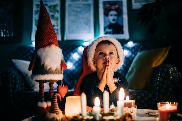A child prays in front of Christmas candles.