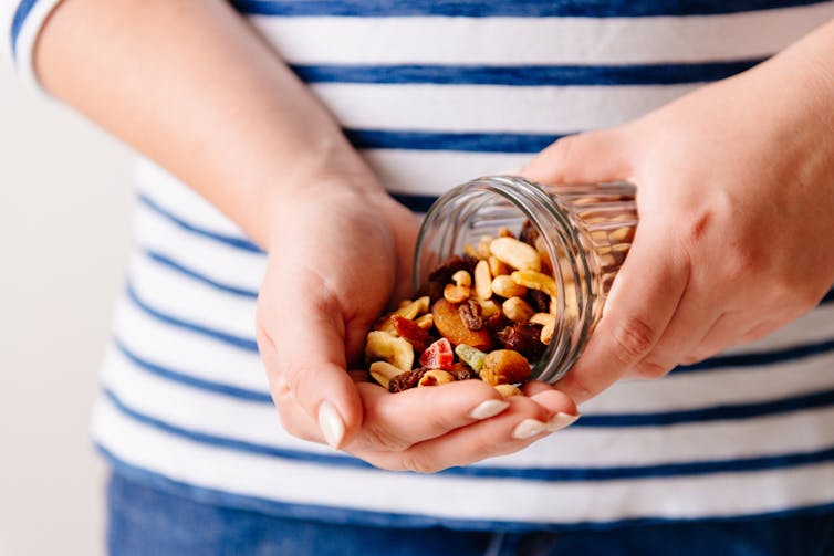 Woman tipping out nut mix into palm of hand
