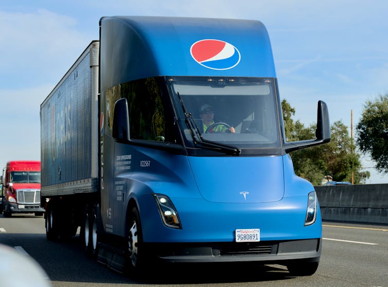 A blue Pepsi electric truck drives on the highway