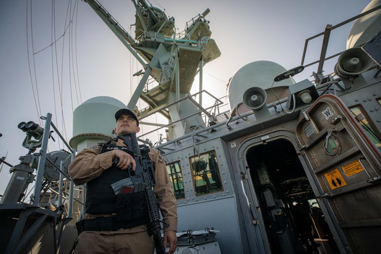 An American marine stands guard on the deck of the guided-missile destroyer USS Carney in the Red Sea, December 2023.