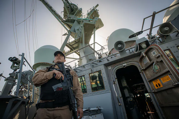 An American marine stands guard on the deck of the guided-missile destroyer USS Carney in the Red Sea, December 2023.