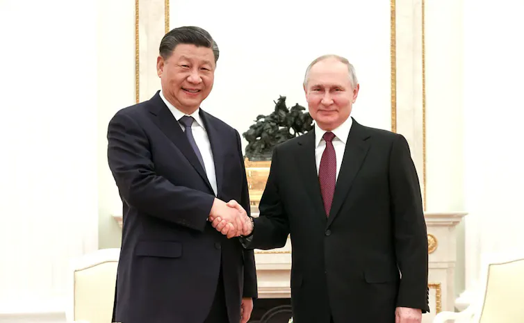 Presidents Putin and Xi shake hands.