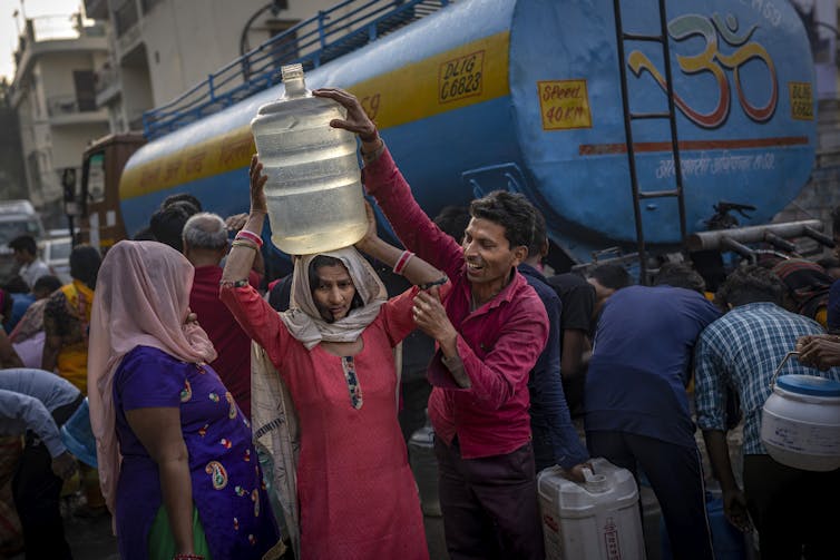 People collect drinking water from a mobile water tanker.