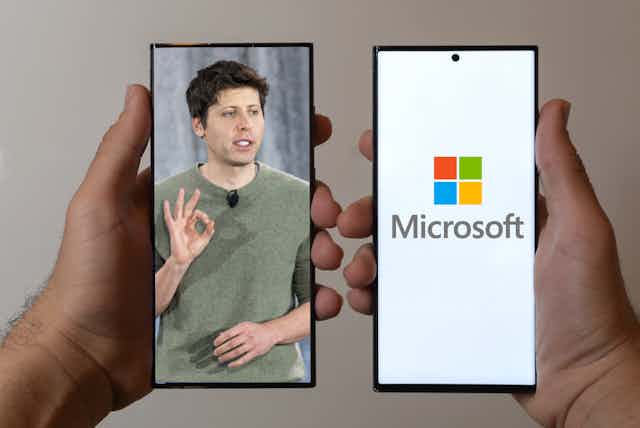 Two hands holding smarphones, one with an image of Sam Altman, the other with a Microsoft logo.